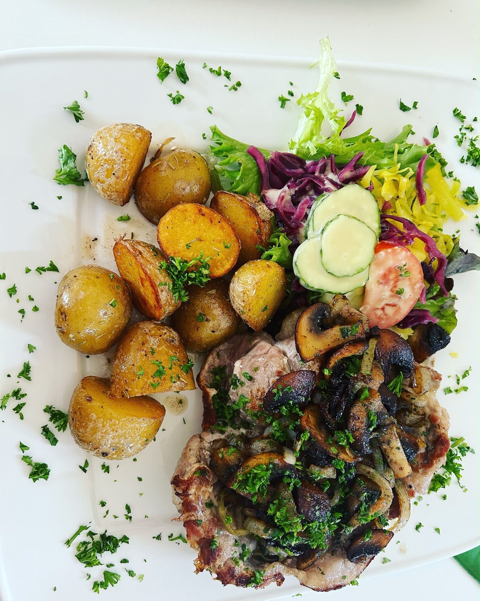 Een bord eten met geroosterde aardappelen, vleesgerecht en salade.