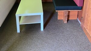 Ein Holzblockbau-Innenraum mit einer grünen Bank, einem weißen Tisch und einer Heizung.