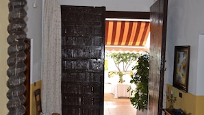 An open wooden door leading to a dining area with a table and chairs, a potted plant, and a wall-mounted candelabra. - Moriles Traditional Farmhouse for 8 (Moriles)