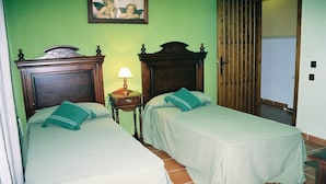 A room with two beds, a nightstand with a lamp, and a wooden door. - Moriles Traditional Farmhouse for 8 (Moriles)