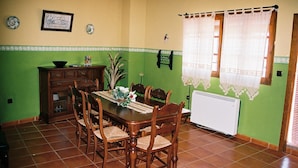 A dining area with a wooden table and chairs, a radiator, and a window with curtains. - Moriles Traditional Farmhouse for 8 (Moriles)