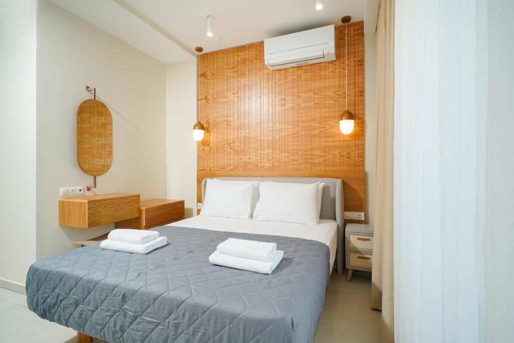 A neatly made bed with a grey quilt, a wooden headboard, and two bedside lamps.