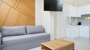 A modern living room with a grey sofa, a wooden coffee table, and a flat-screen TV mounted on the wall. - Valen Mare Suites (Thasos)