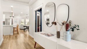 Una cocina moderna con armarios blancos, un refrigerador de acero inoxidable y una mesa de comedor de madera con sillas.