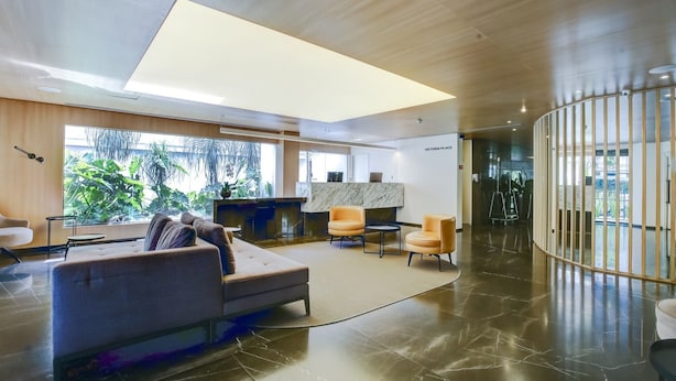 A modern lobby with a reception desk, seating area, and large windows offering a view of greenery. - 360 Itaim Bibi (São Paulo)