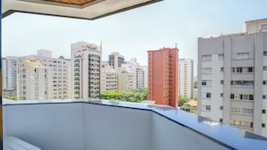 A balcony with a view of high-rise buildings, including a distinctive red tower. - 360 Itaim Bibi (São Paulo)
