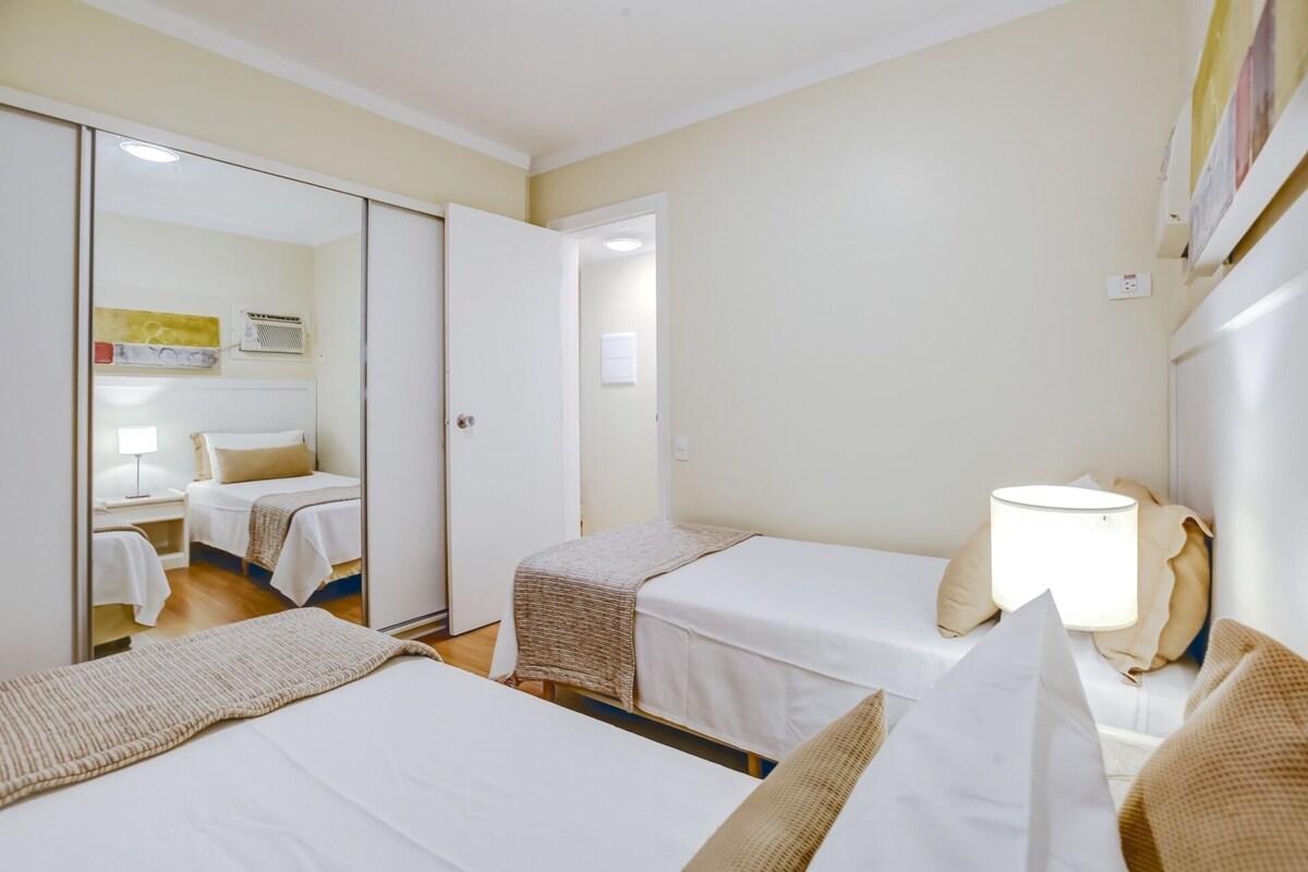 Una habitación de hotel con dos camas, un espejo, una lámpara y un cuadro en la pared.