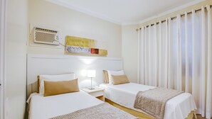 A hotel room with two beds, a bedside table with a lamp, a ceiling fan, and a window with curtains. - 360 Itaim Bibi (São Paulo)
