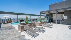 Uma área de piscina no terraço, com espreguiçadeiras, piscina e vista da cidade.