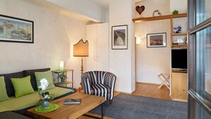 A living room with a sofa, armchair, coffee table, and a TV stand. - Apartment Azalea – Arrive, Feel at Home, Discover the Ötztal – Comfort in Central Oetz (Oetz)