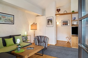 Una sala de estar con sofá, sillón, mesa de centro y mueble para televisión.