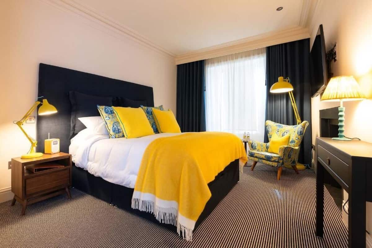 Una habitación de hotel con una cama grande, una silla, un escritorio y un televisor.