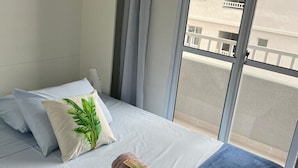 Hotellihuone, jossa on sänky, ikkuna, josta on näkymä rakennukseen, ja verho.