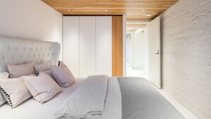 A bedroom with a tufted headboard, a bed with multiple pillows, and a wooden ceiling. - Nordic Design with Sauna in Cental Helsinki (Kamppi) (Helsinki)