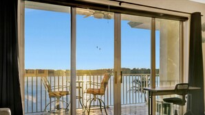 Ein Zimmer mit einer Schiebeglastür, die auf einen Balkon mit Stühlen und einem Tisch führt.
