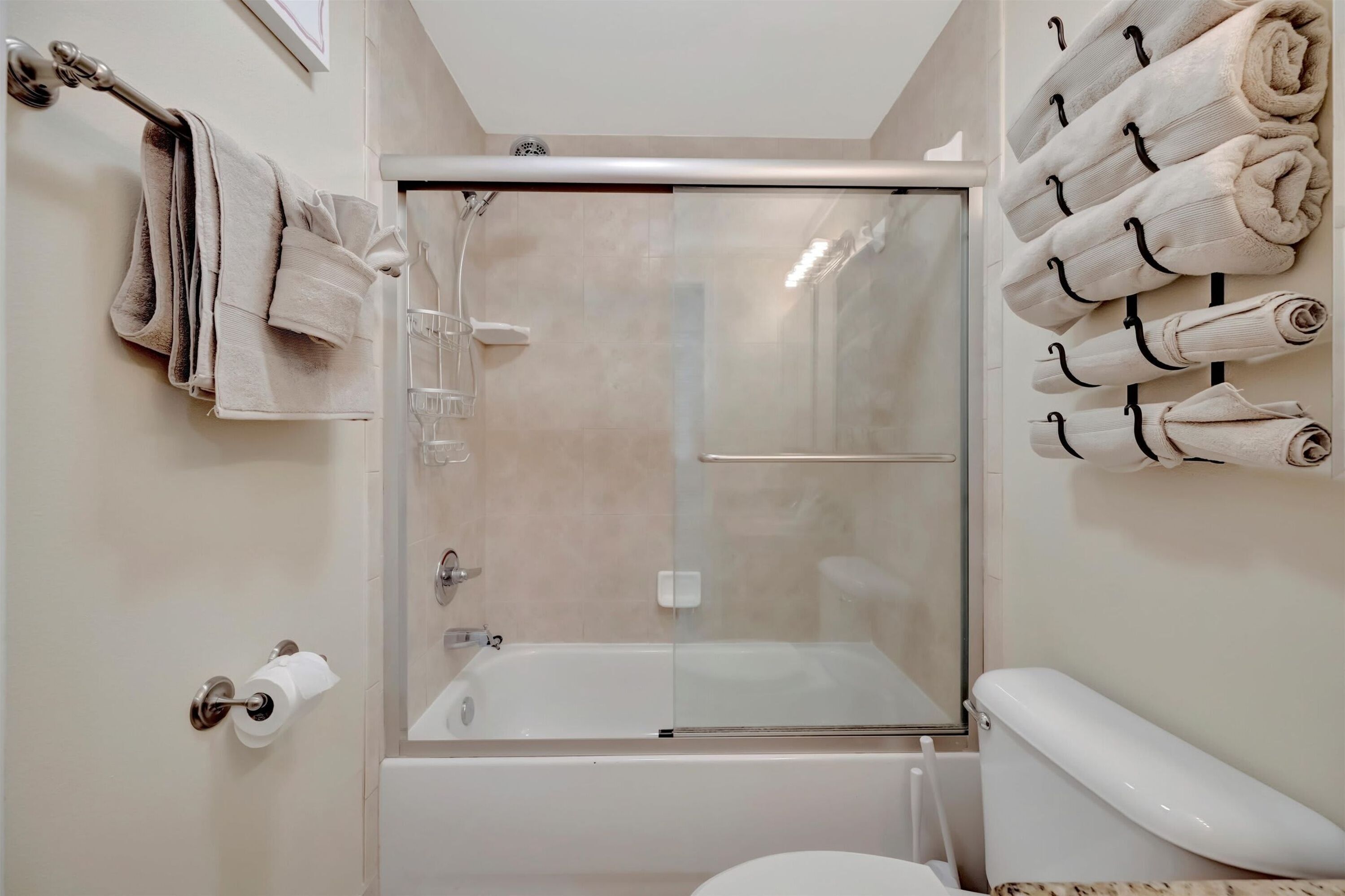 Un bagno moderno con doccia a vetro, un water e un porta asciugamani con asciugamani ripiegati.
