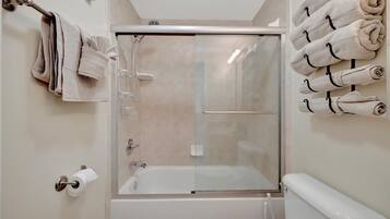 Un bagno moderno con doccia a vetro, un water e un porta asciugamani con asciugamani ripiegati.