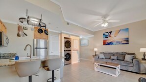 Eine moderne Küche mit Einbauofen und Kühlschrank, ein Essbereich mit Sofa und Couchtisch sowie ein Hauswirtschaftsraum mit Waschmaschine.