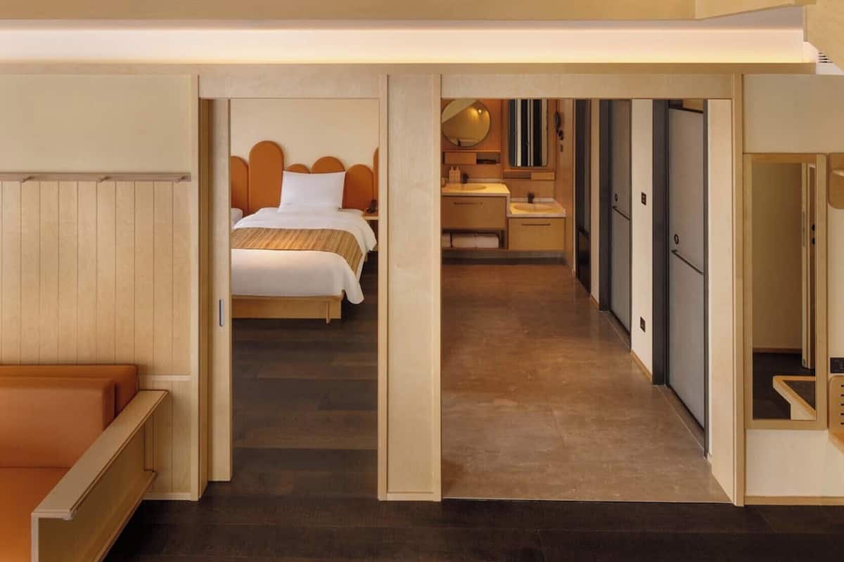 Ein modernes Hotelzimmer mit einer Erker-Schlafzone, einem separaten Badezimmer und einem begehbaren Kleiderschrank.