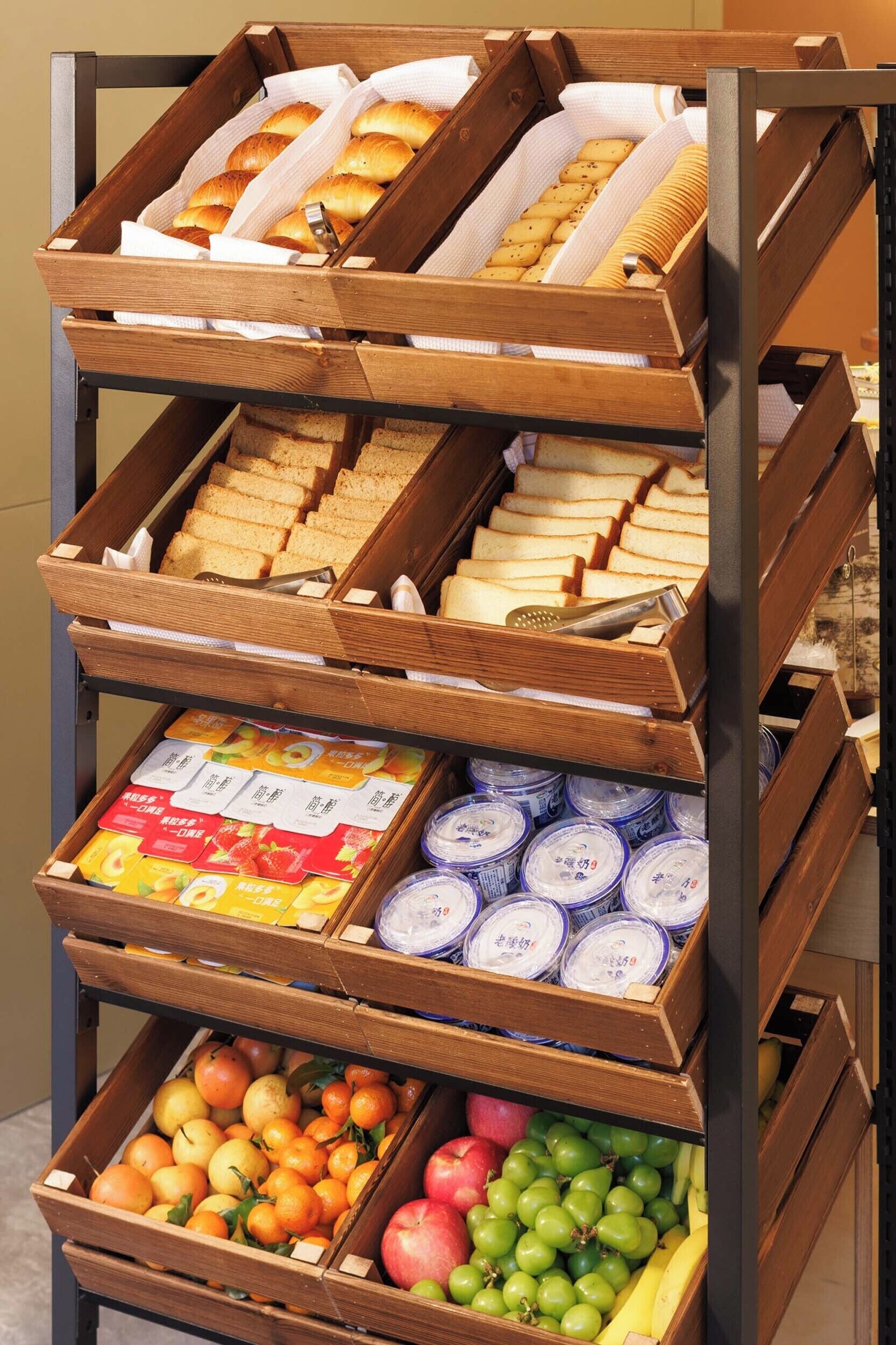Una estructura de madera escalonada con diversos productos alimenticios, como pan, pasteles y frutas.