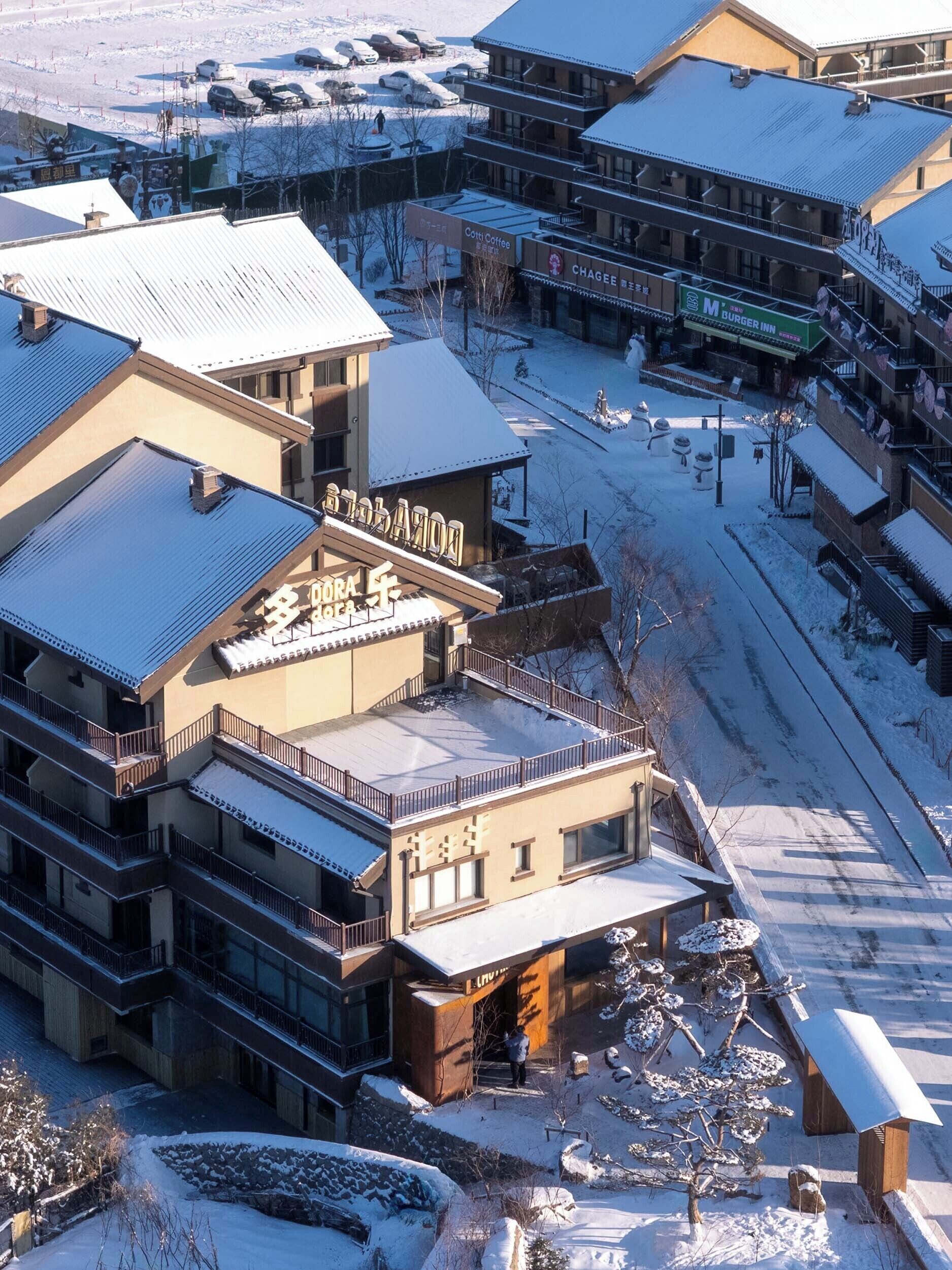 A multi-story building with a snow-covered roof and a sign that reads "Chagge Coffee."