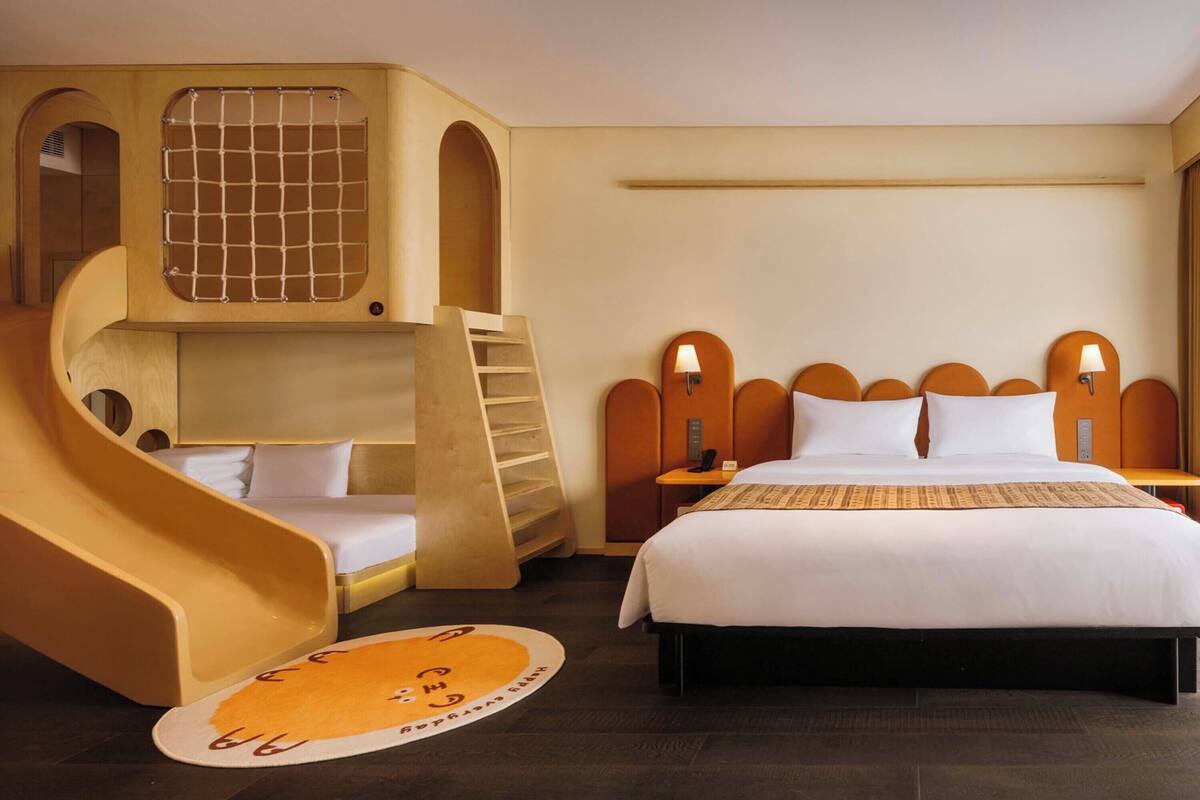 Ein Zimmer mit einem Bett, einer kleinen Couch, einer Rutsche und einem Fenster mit Gittermuster.