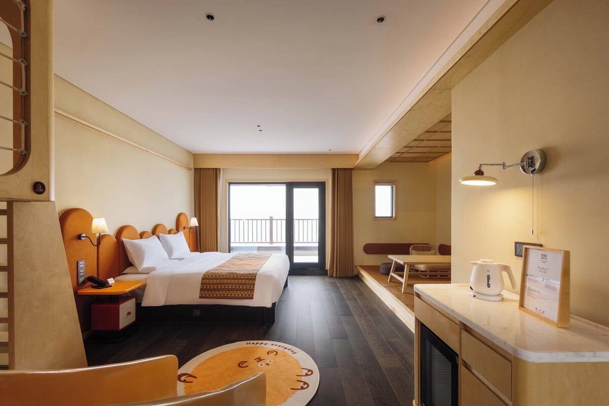 Ein Hotelzimmer mit Bett, Nachttisch, Lampe und Blick auf den Balkon.