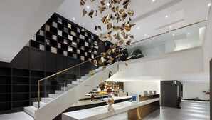 Un interior moderno con una escalera, un mostrador de recepción y una estantería.