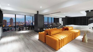Una sala de estar moderna con un sofá grande, una mesa de centro y vistas a la ciudad a través de amplias ventanas.