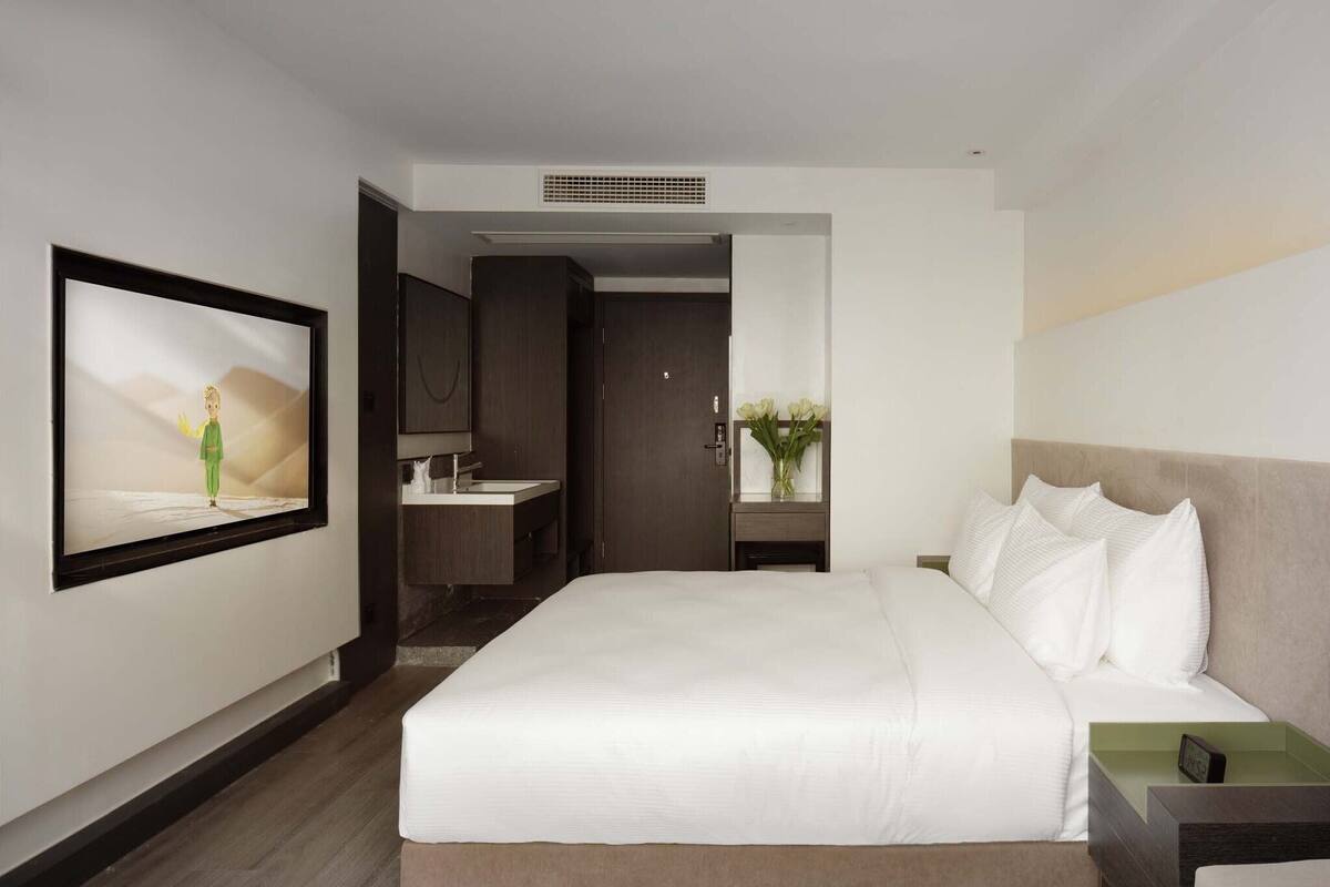 Una habitación de hotel con una cama grande, televisión, baño y vistas al exterior.