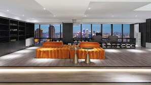 Una sala de estar moderna con vistas a la ciudad, que incluye un conjunto de sofás, dos mesitas auxiliares y una estantería.