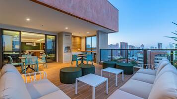 Un espacio exterior moderno con zona de comedor, asientos y vistas al horizonte de la ciudad.