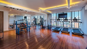 A spacious gym with wooden flooring, various exercise equipment, and large windows offering a city view. - Jsmart Studio #1106 - Comfortable apt by Carpediem (Fortaleza)
