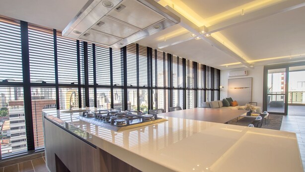 A modern kitchen with a large island, large windows, and a view of the city. - Jsmart Studio #1106 - Comfortable apt by Carpediem (Fortaleza)