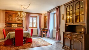 Une salle à manger avec une table dressée pour deux personnes, un lustre et un buffet aux portes vitrées.