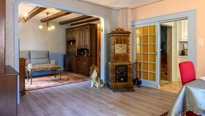 Un salon avec un canapé, une table basse en bois, un chien, une radio ancienne et un fauteuil rouge.