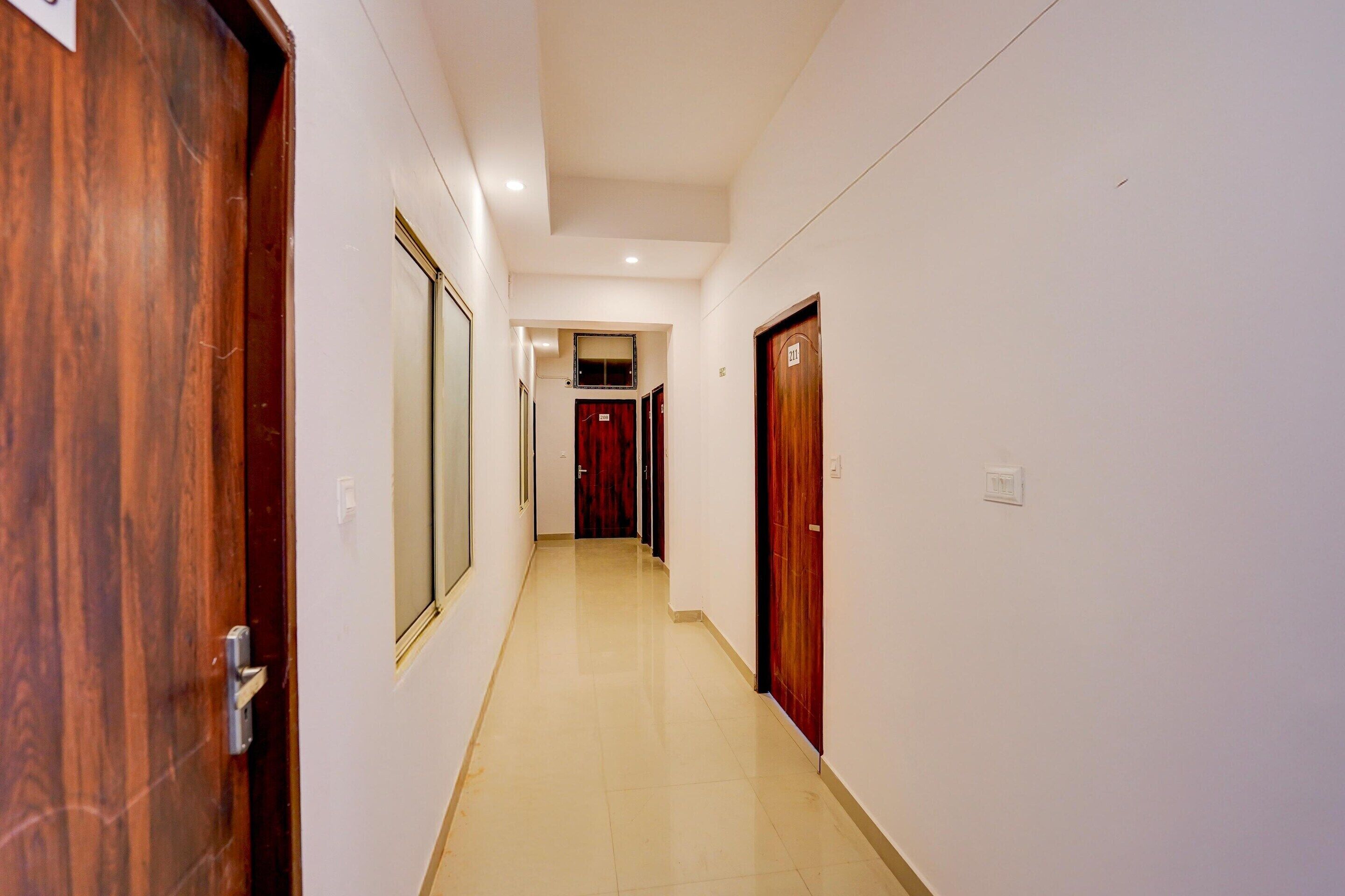A corridor with wooden doors, a tiled floor, and a ceiling with recessed lighting.
