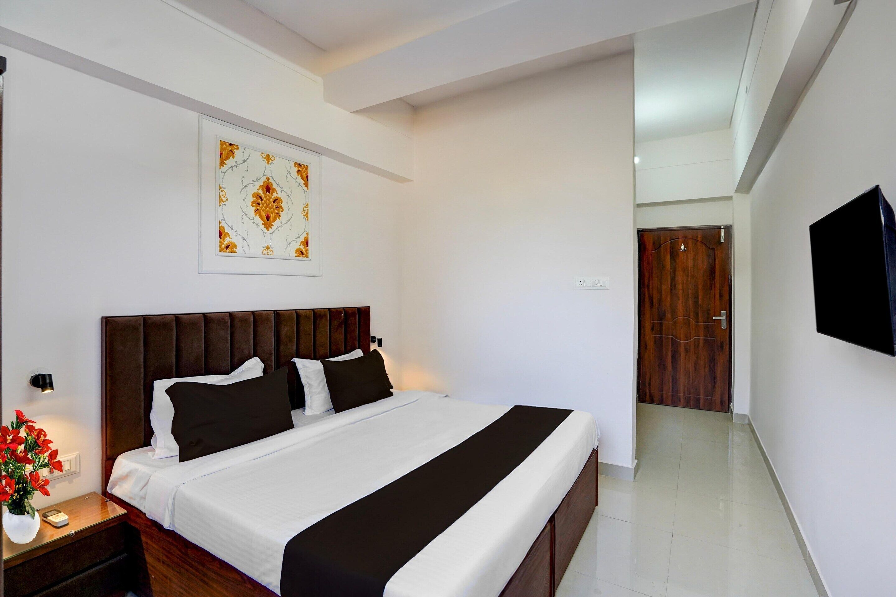 A neatly arranged bedroom with a bed, bedside table, and a wall-mounted TV.