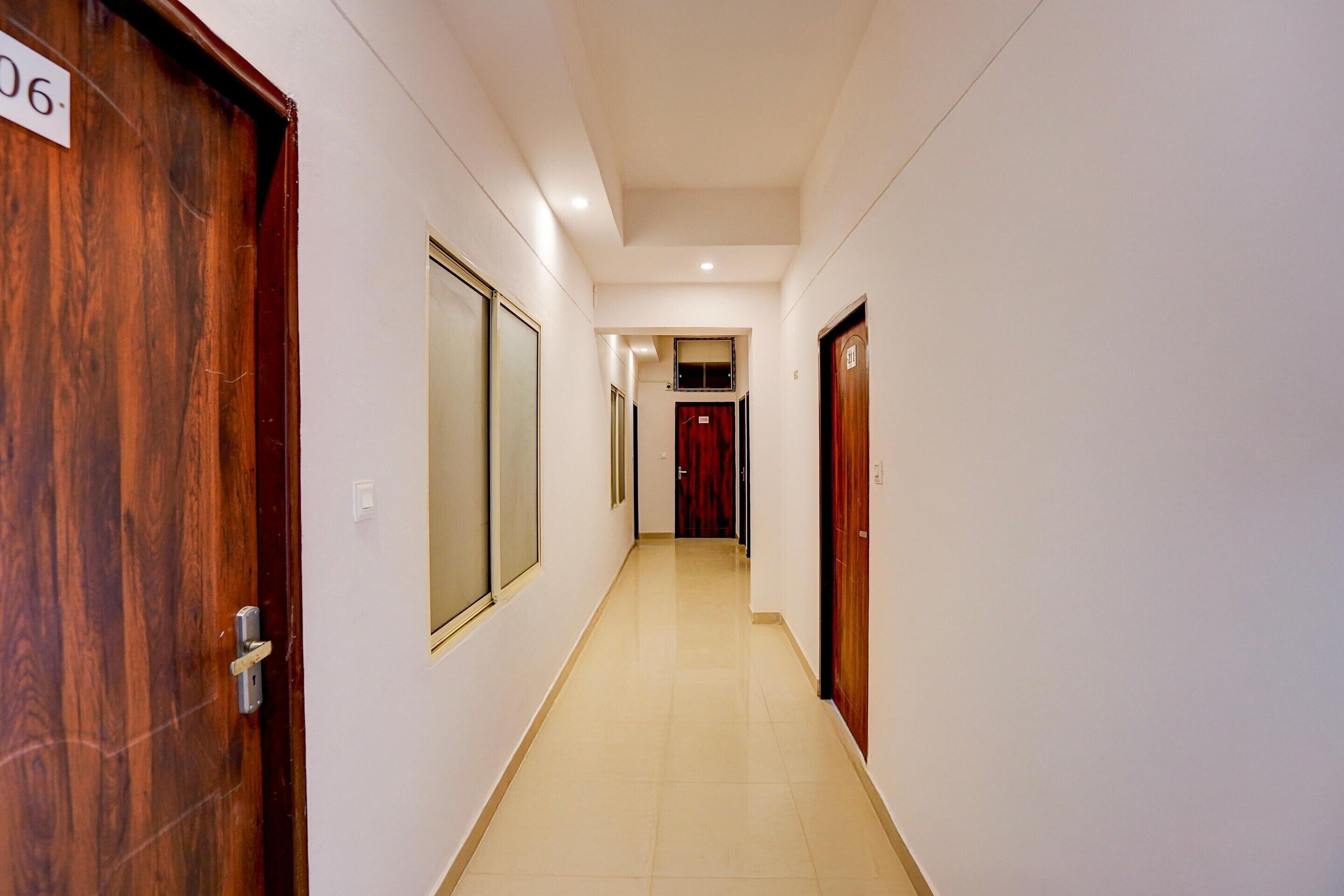 A hallway with a wooden door labeled '06', a mirrored door, and a red door at the end.