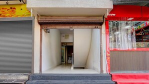 Ein Schaufenster mit heruntergelassenem Rollo, eine Treppe, die zu einer Tür führt, und ein rotes Markisen