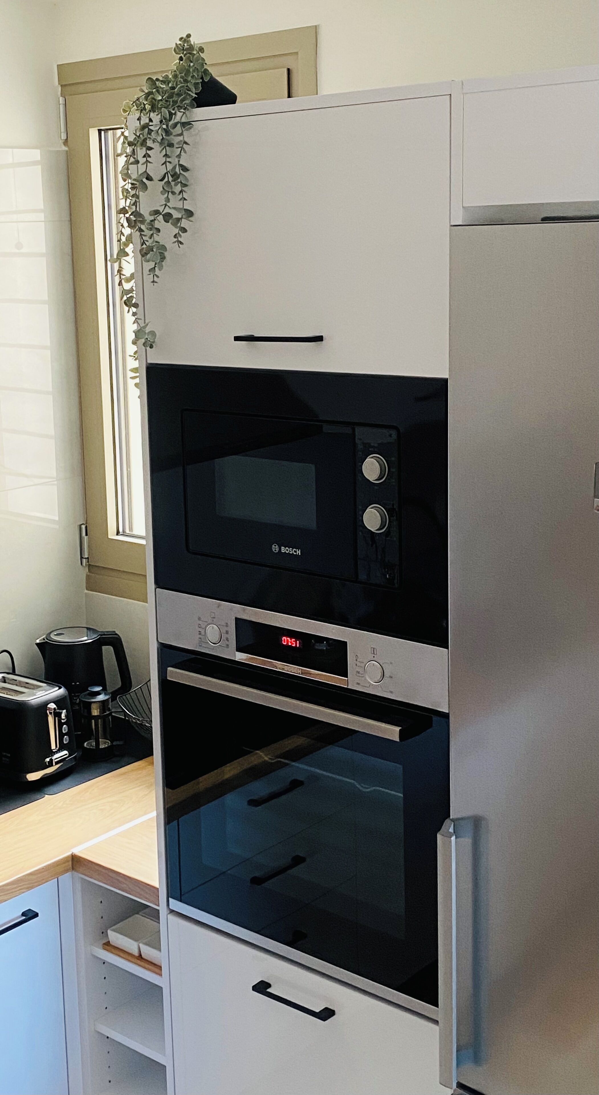 A kitchen with a built-in oven, a microwave, and a coffee maker on the counter.