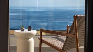 A balcony with a view of the ocean, a wicker chair, a small table with a plant and a mug. - Elounda Infinity Blue Luxury Villas (Agios Nikolaos)