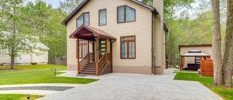 A two-story house with a front porch, a covered patio, and a driveway leading to the entrance.