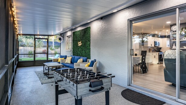 An outdoor patio area with a foosball table, a sofa, and a dining table. - Sunny Urban Escape 3 Bedroom Home (Sarasota)