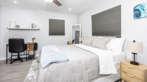 A bedroom with a bed, a desk, a chair, a nightstand, a lamp, a ceiling fan, and a window with blinds. - Sunny Urban Escape 3 Bedroom Home (Sarasota)