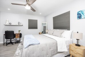 A bedroom with a bed, a desk, a chair, a nightstand, a lamp, a ceiling fan, and a window with blinds. - Sunny Urban Escape 3 Bedroom Home (Sarasota)
