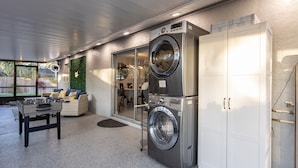 A laundry room with two stacked front-loading washing machines, a white cabinet, and a foosball table. - Sunny Urban Escape 3 Bedroom Home (Sarasota)