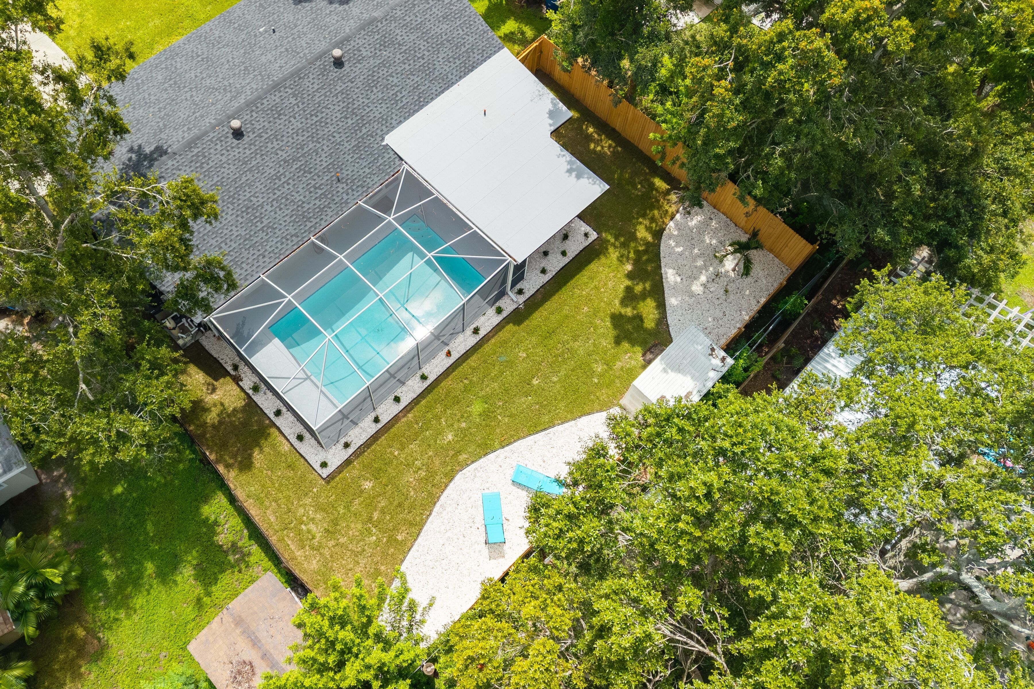 Vue aérienne d’une maison moderne dotée d’une piscine, entourée d’une pelouse bien entretenue et d’arbres.