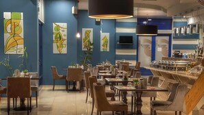 Ein modernes Restaurant mit blauen Wänden, abstrakter Kunst und verschiedenen Sitzmöglichkeiten.