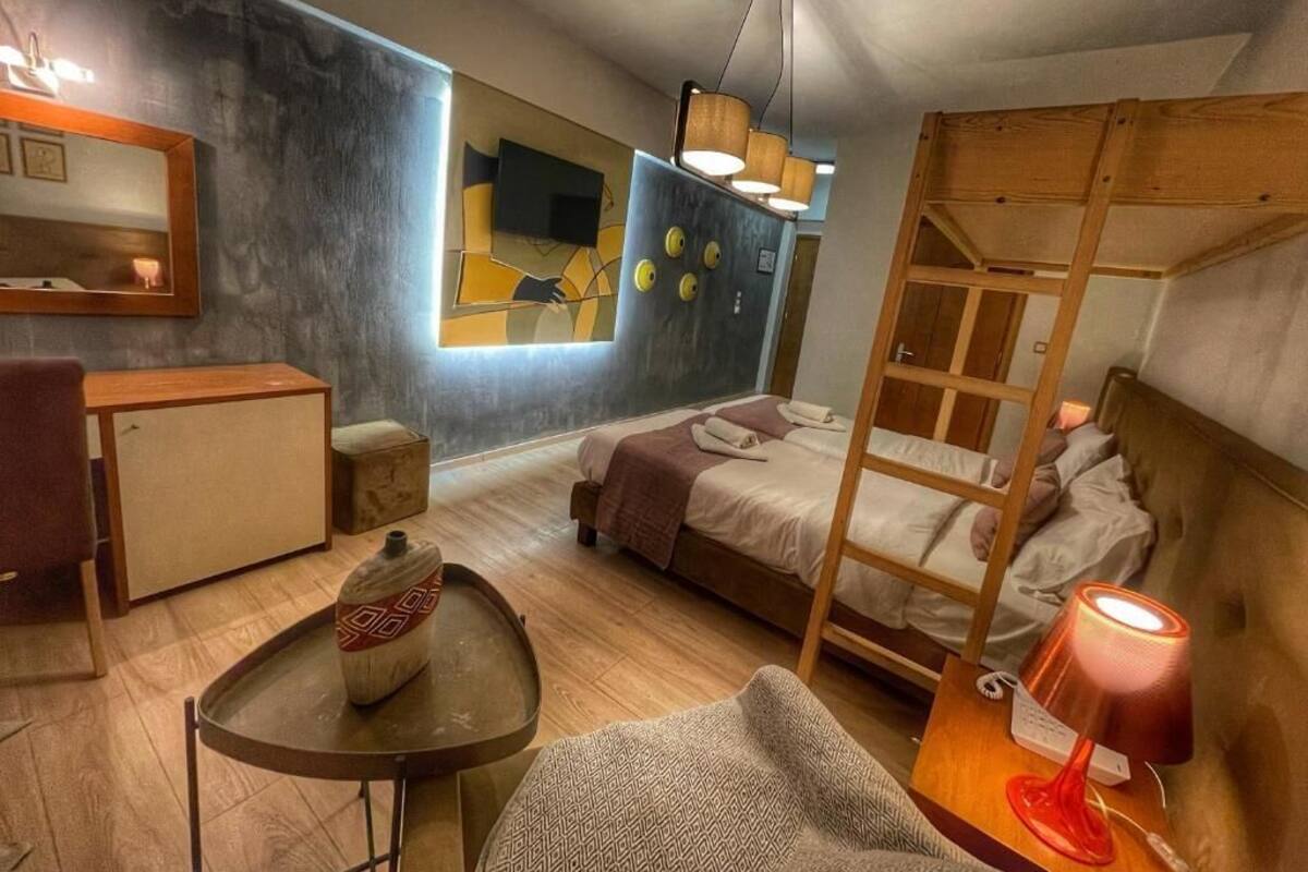 Une chambre d’hôtel de taille réduite, équipée d’un lit superposé, d’un petit bureau, d’une chaise, d’une table et d’une lampe.